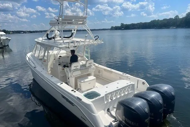 The Image of 2011 Everglades 350LX boat with triple Yamaha engines on a calm lake. - 1