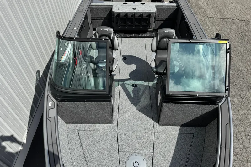 Slide: The Image of 2026 Lund 1875 Fisherman boat interior with dual seats and windshield, docked on pavement. - 5