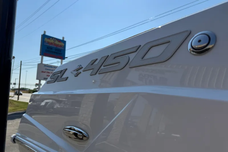 Slide: The Image of 2026 Supra SL 450 boat emblem in sunlight, dealership sign in background. - 10