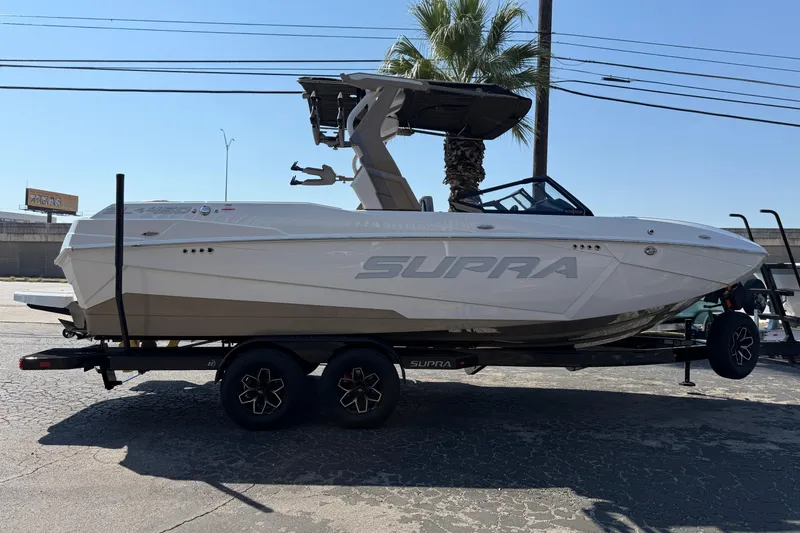 Slide: The Image of 2026 Supra SL 450 boat on trailer, parked outdoors under clear sky. - 8