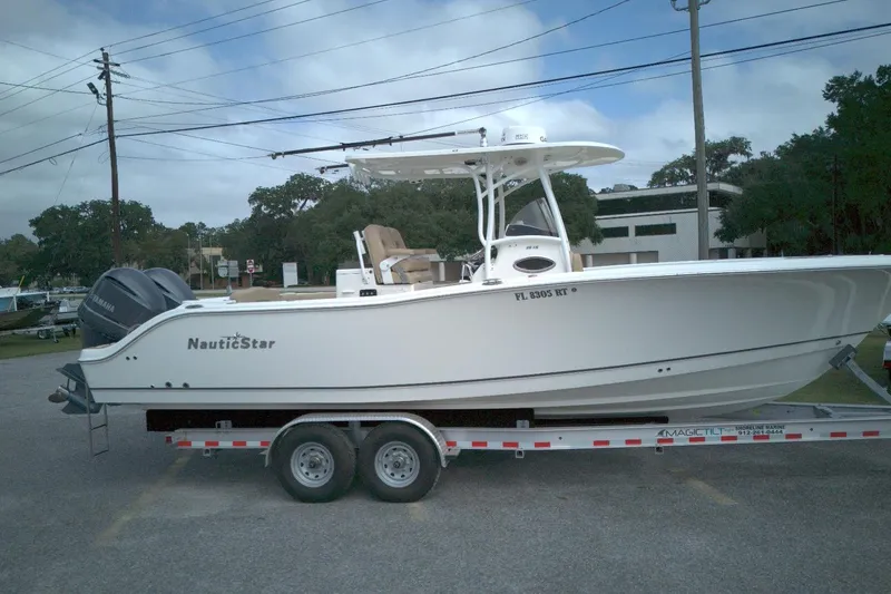 The Image of 2019 NauticStar 28 XS boat on trailer, parked outdoors, side view. - 0