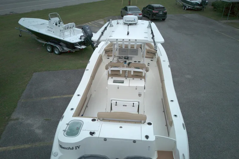 Slide: The Image of 2019 NauticStar 28 XS boat, aerial view, parked on pavement with nearby vehicles. - 11
