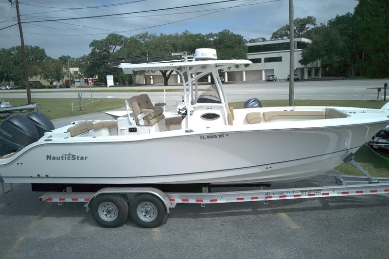 Slide: The Image of 2019 NauticStar 28 XS boat on trailer, parked outdoors. - 2