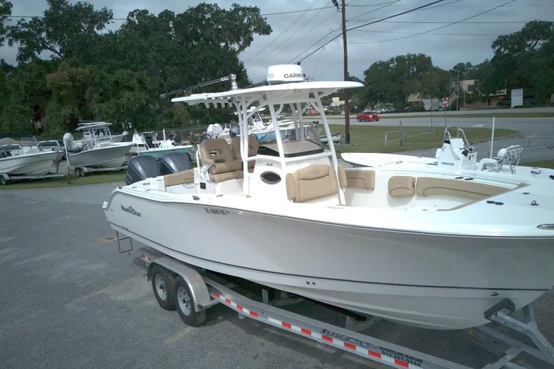 Slide: The Image of 2019 NauticStar 28 XS boat on trailer, parked outdoors, surrounded by trees and other boats. - 5