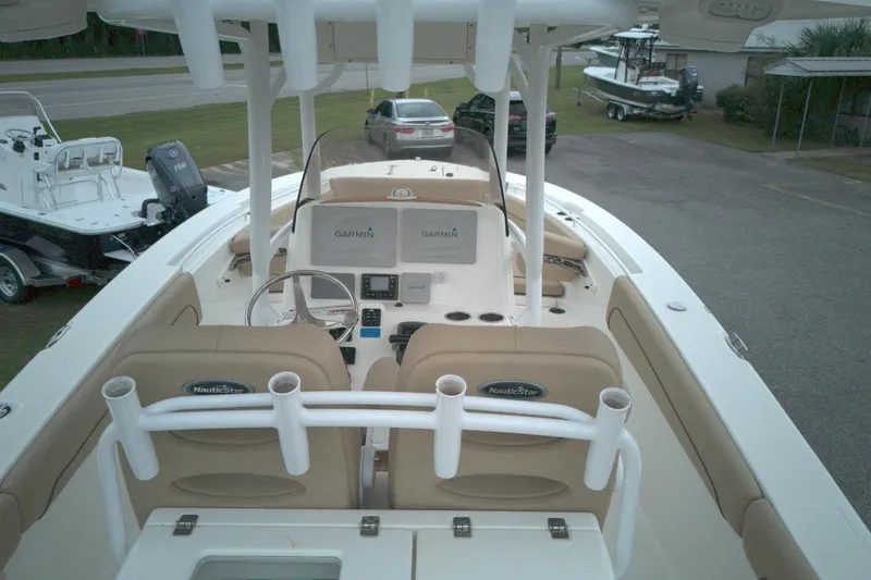 Slide: The Image of 2019 NauticStar 28 XS boat interior with Garmin navigation, beige seating, and rod holders. - 7