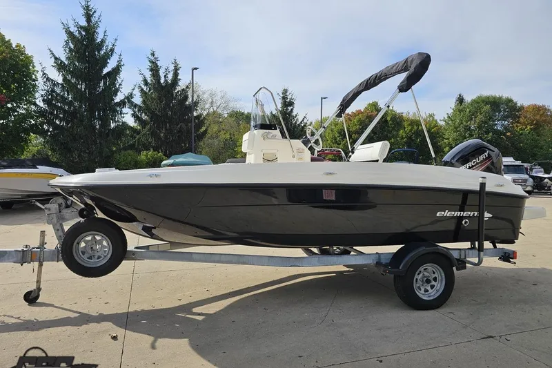 Slide: The Image of 2016 Bayliner Element F18 boat on trailer, parked outdoors with trees in background. - 27