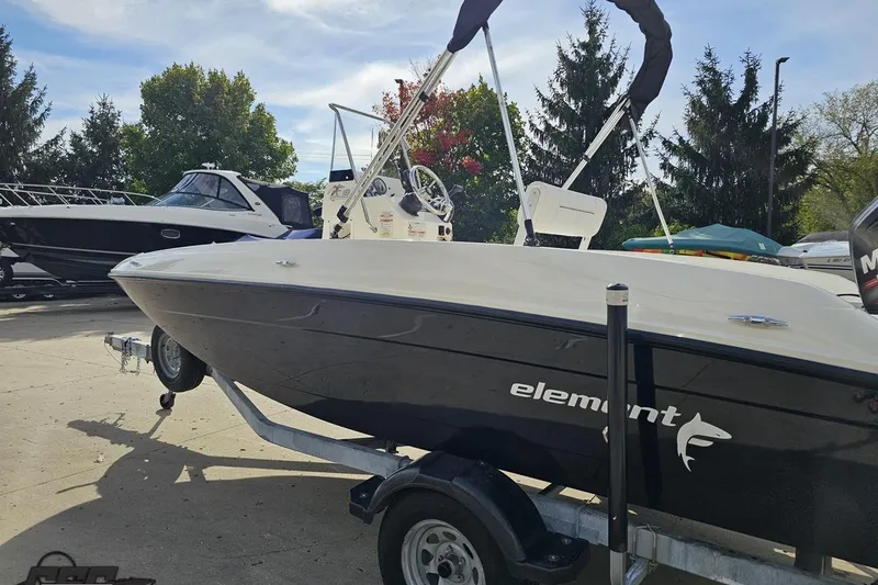 Slide: The Image of 2016 Bayliner Element F18 boat on trailer, parked outdoors with trees in background. - 33