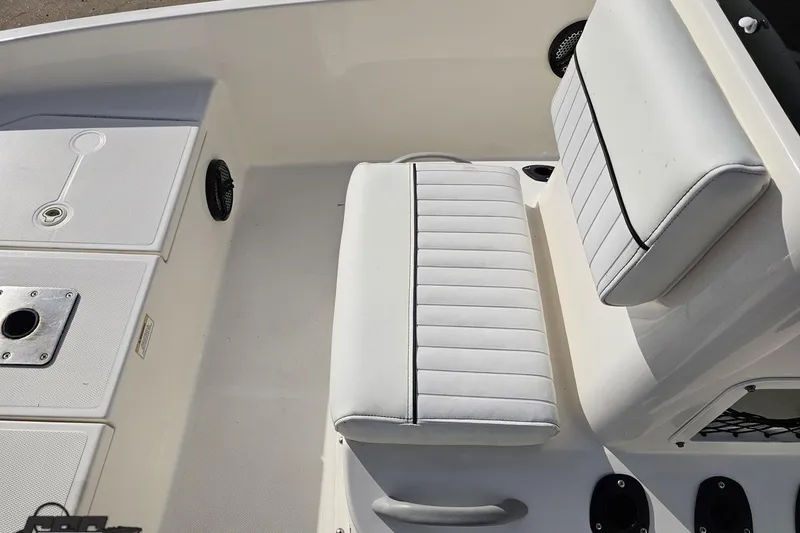 Slide: The Image of 2016 Bayliner Element F18 boat interior with white cushioned seating and storage compartments. - 74