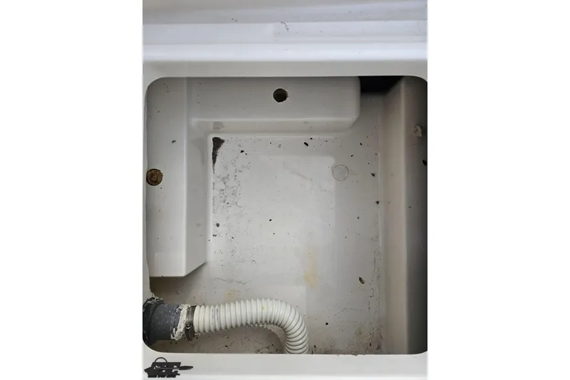 Slide: The Image of 2016 Bayliner Element F18 boat compartment with drainage hose and visible dirt. - 90