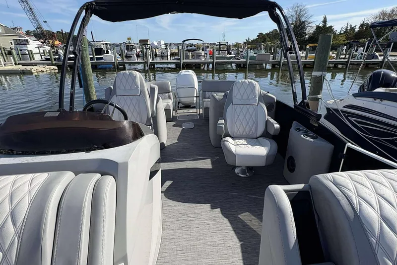 Slide: The Image of 2021 Bennington 27RX pontoon boat interior with luxurious seating at a marina. - 3