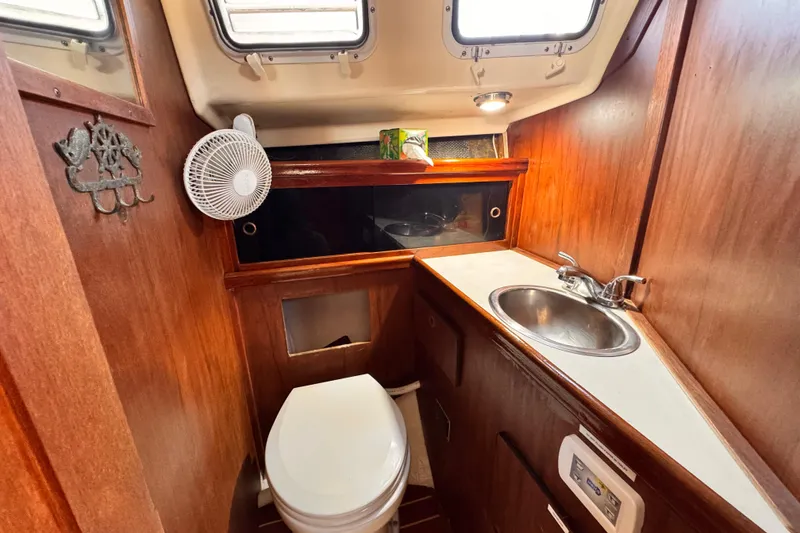 Slide: The Image of 1979 O'Day 37 Center Cockpit bathroom with sink, toilet, and wooden cabinetry. - 11