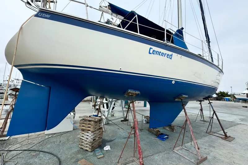 Slide: The Image of 1979 O'Day 37 Center Cockpit sailboat on stands, blue and white hull, marina background. - 34