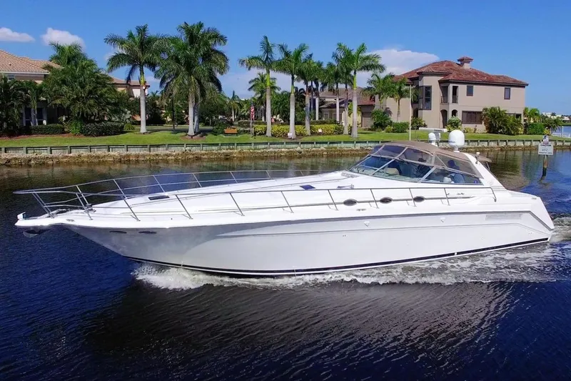 Slide: The Image of 1995 Sea Ray 500 Sundancer yacht cruising near waterfront homes and palm trees. - 4