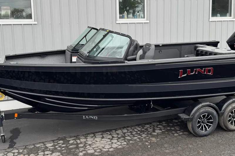 The Image of 2026 Lund 2075 Fisherman boat on trailer, sleek black design, parked outdoors. - 0