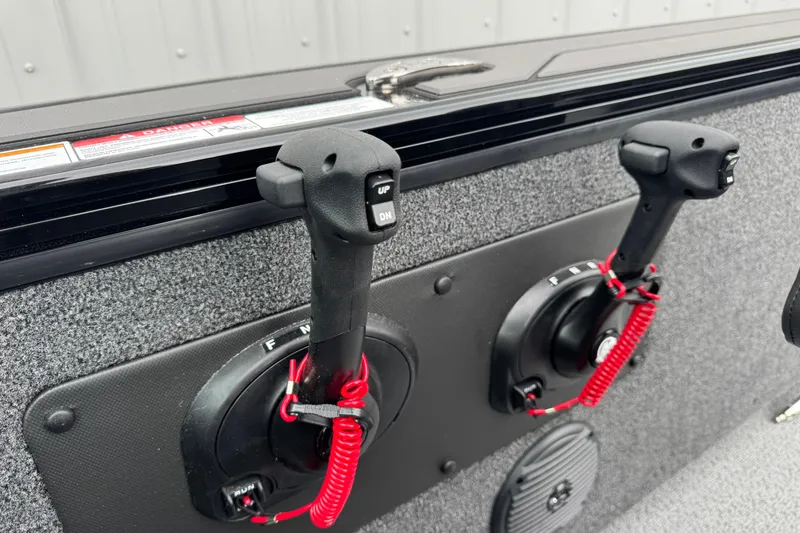 Slide: The Image of 2026 Lund 2075 Fisherman boat controls with red safety lanyards and textured panel. - 12