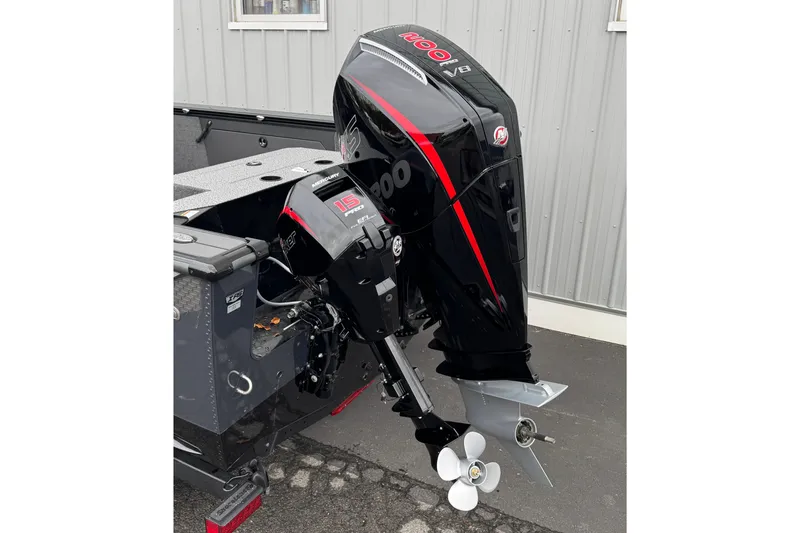 Slide: The Image of 2026 Lund 2075 Fisherman boat with powerful Mercury outboard motor, parked on pavement. - 2
