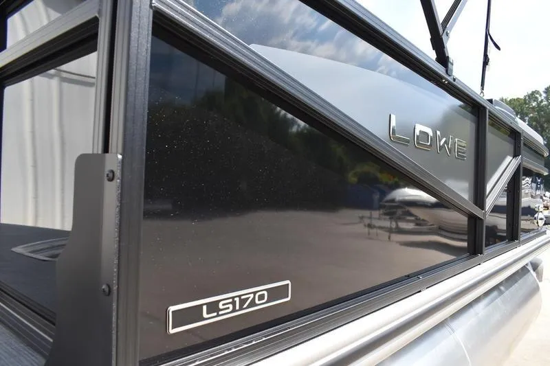 Slide: The Image of 2026 Lowe LS 170 pontoon boat on trailer, black exterior, parked outdoors. - 2
