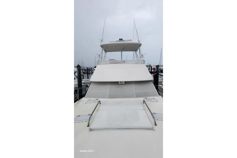 Slide: The Image of 2006 Riviera 47 Open Flybridge Series II yacht docked at marina under cloudy sky. - 16