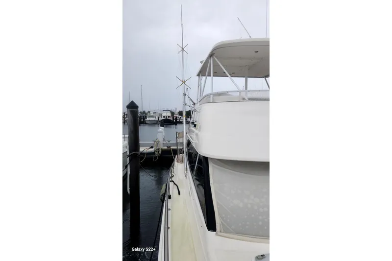 Slide: The Image of 2006 Riviera 47 Open Flybridge Series II docked at marina on a cloudy day. - 18