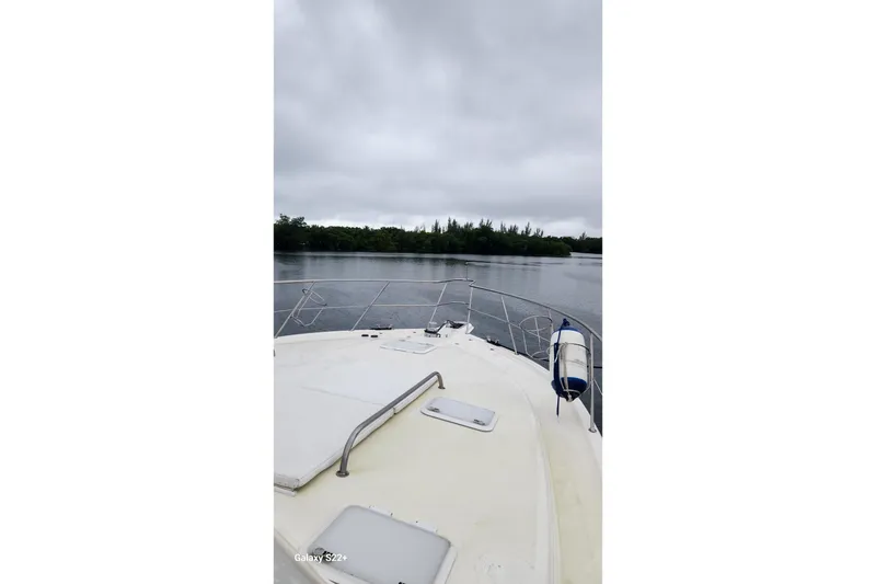 Slide: The Image of 2006 Riviera 47 Open Flybridge boat on calm water under cloudy sky. - 25