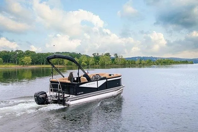 Slide: The Image of 2026 Lowe LS 170 pontoon boat cruising on a serene lake under a partly cloudy sky. - 4