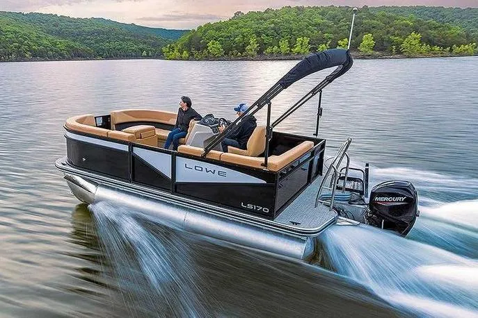 Slide: The Image of 2026 Lowe LS 170 pontoon boat cruising on a scenic lake with lush green hills. - 5
