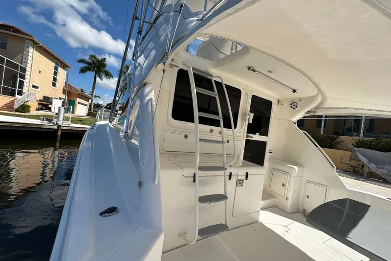 Slide: The Image of 2002 Riviera 40 Flybridge yacht docked, showcasing sleek design and spacious deck area. - 17