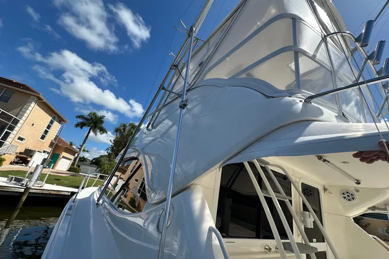 Slide: The Image of 2002 Riviera 40 Flybridge yacht docked under clear blue sky, with palm trees nearby. - 18