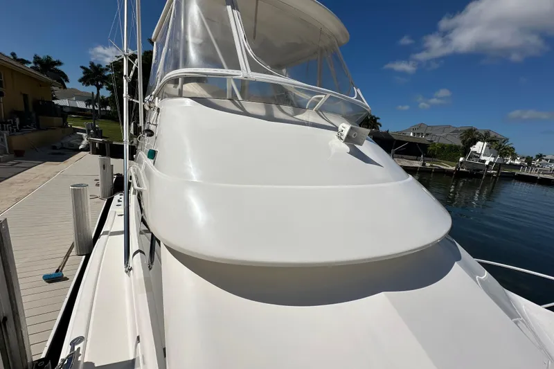 Slide: The Image of 2002 Riviera 40 Flybridge yacht docked, showcasing sleek design and clear skies. - 21