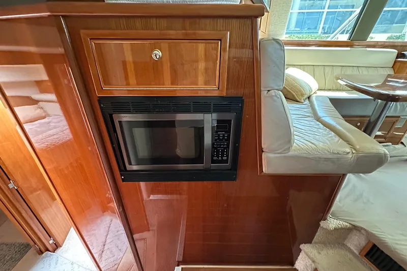 Slide: The Image of 2002 Riviera 40 Flybridge interior with microwave, wooden cabinetry, and cushioned seating area. - 35