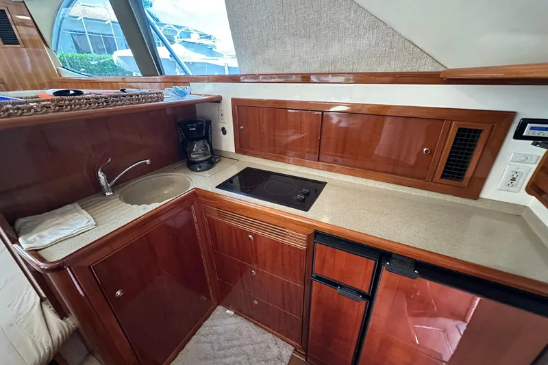 Slide: The Image of 2002 Riviera 40 Flybridge yacht kitchen with wood cabinetry, sink, stove, and mini fridge. - 36