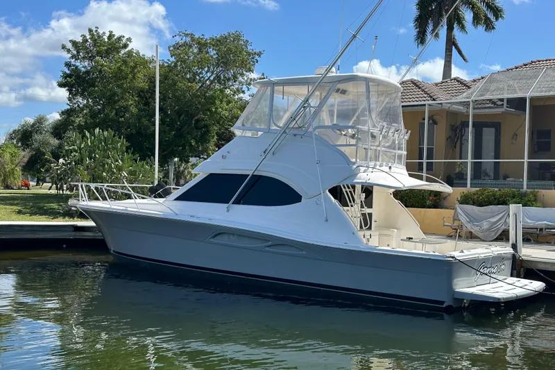 Slide: The Image of 2002 Riviera 40 Flybridge yacht docked by a waterfront home. - 49