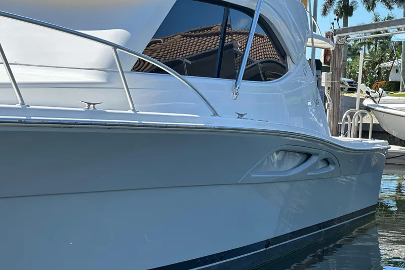 Slide: The Image of 2002 Riviera 40 Flybridge yacht docked, showcasing sleek design and polished exterior. - 6