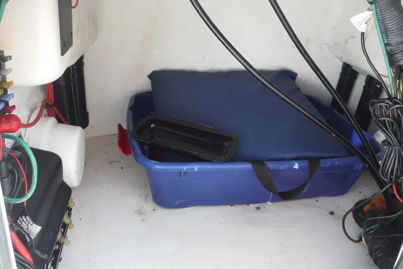 Slide: The Image of Storage compartment of a 2007 Boston Whaler 180 Dauntless with cables and a blue container. - 16