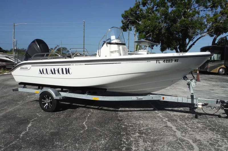 Slide: The Image of 2007 Boston Whaler 180 Dauntless boat on trailer, labeled "AQUAHOLIC," parked outdoors. - 2