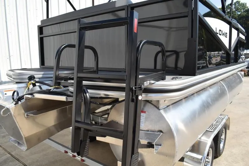 Slide: The Image of 2026 Lowe LS 170 pontoon boat with ladder and trailer, parked outdoors. - 4