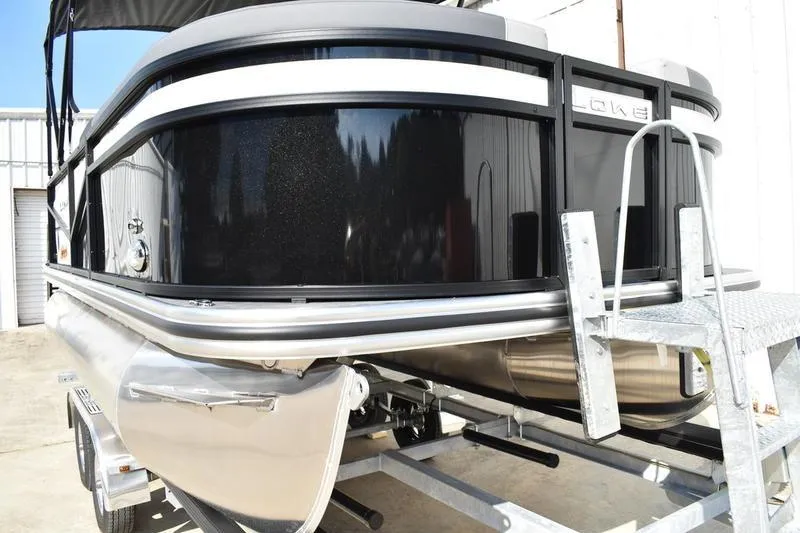 Slide: The Image of 2026 Lowe LS 170 pontoon boat on trailer, black exterior, parked outdoors. - 8