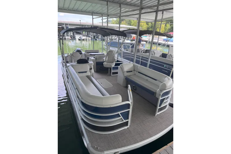 The Image of 2024 Godfrey SWEETWATER 2486 DT pontoon boat docked under a covered marina. - 1