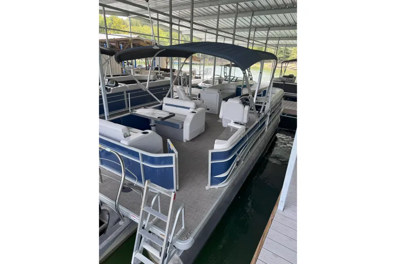 Slide: The Image of 2024 Godfrey SWEETWATER 2486 DT pontoon boat docked under a covered marina. - 5