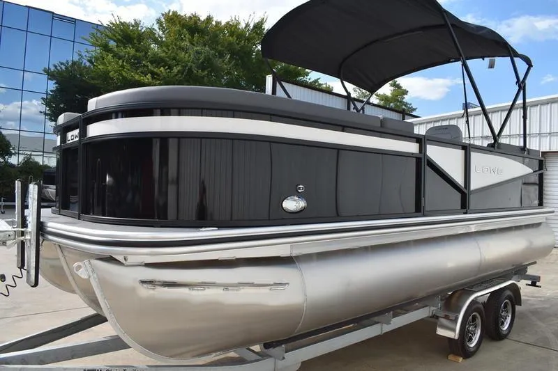 Slide: The Image of 2026 Lowe LS 210 WT pontoon boat on trailer, black and silver design, outdoor setting. - 6