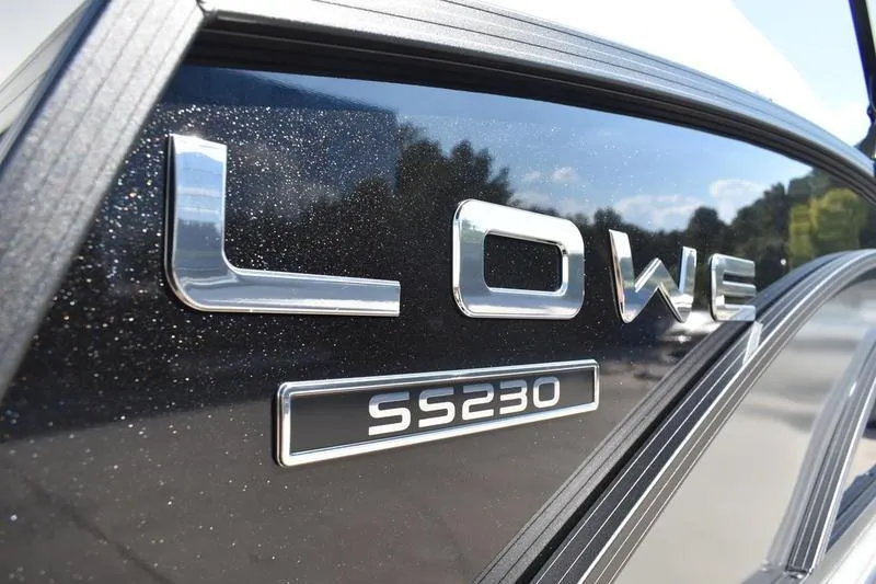 Slide: The Image of 2026 Lowe SS 230 pontoon boat on trailer with ladder, parked outdoors. - 7