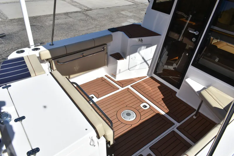 Slide: The Image of 2024 Ranger Tugs R-27 boat deck with teak flooring and seating area. - 17