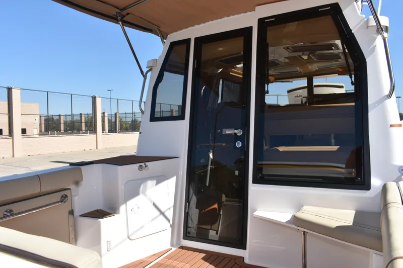 Slide: The Image of 2024 Ranger Tugs R-27 boat interior with seating and glass door. - 18