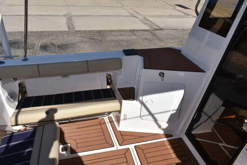Slide: The Image of 2024 Ranger Tugs R-27 boat interior with cushioned seating and wood-patterned flooring. - 19