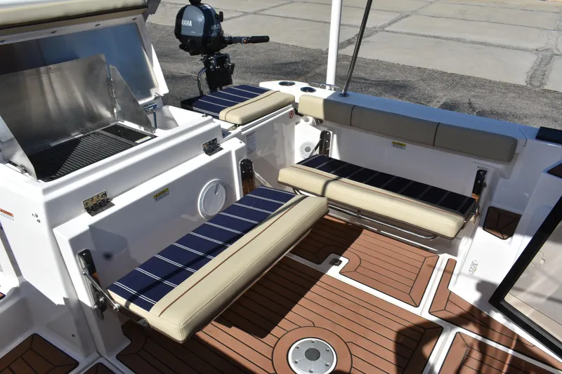 Slide: The Image of 2024 Ranger Tugs R-27 boat interior with seating and grill, featuring teak-style flooring. - 24