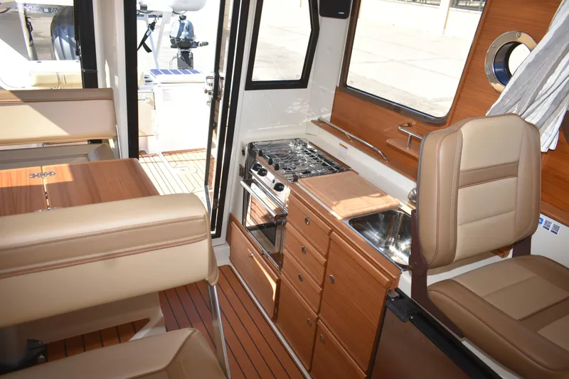 Slide: The Image of 2024 Ranger Tugs R-27 interior with kitchen, seating, and wood finish. - 35