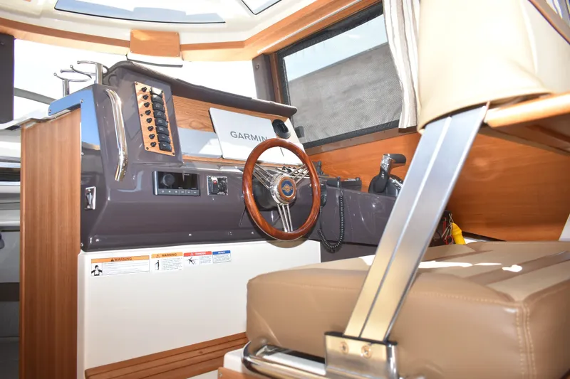 Slide: The Image of 2024 Ranger Tugs R-27 helm with Garmin navigation, wood accents, and leather seating. - 37