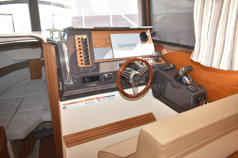 Slide: The Image of 2024 Ranger Tugs R-27 helm with Garmin navigation, wood accents, and comfortable seating. - 39