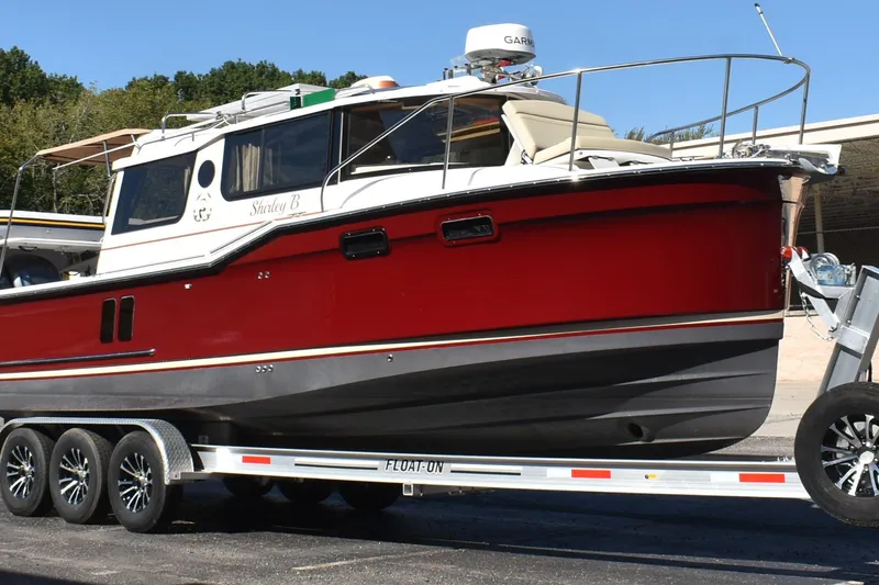 Slide: The Image of 2024 Ranger Tugs R-27 boat on trailer, red and white design, parked outdoors. - 4