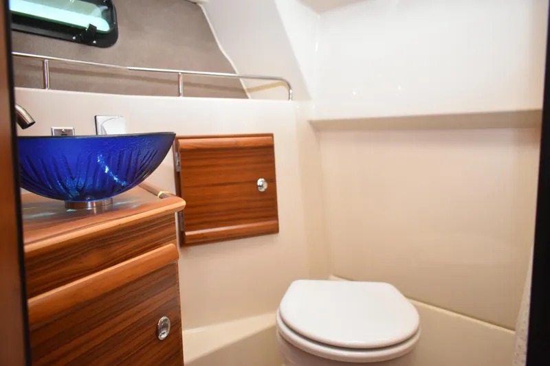 Slide: The Image of 2024 Ranger Tugs R-27 bathroom with blue glass sink and wooden cabinetry. - 44
